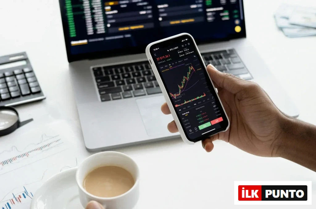 Bir kişi, mobil uygulama üzerinden kripto para grafiklerini incelerken aynı anda dizüstü bilgisayar ekranında piyasa verilerini takip ediyor.