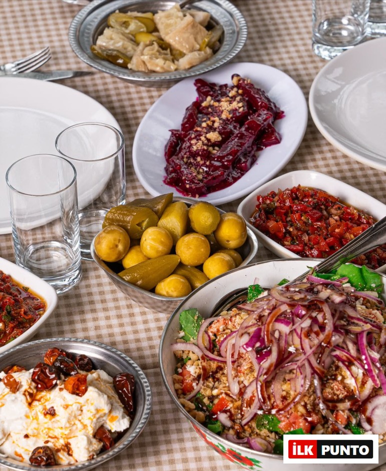 Ankara'nın en iyi meyhanelerinde dost sohbetlerine eşlik eden, üzerinde nar ekşili bol soğanlı salata, pancar ezmesi, turşular ve atom gibi geleneksel lezzetlerin modern sunumlarla buluştuğu zengin bir meze sofrası, kareli masa örtüsünde iştah açıcı görünüyor.