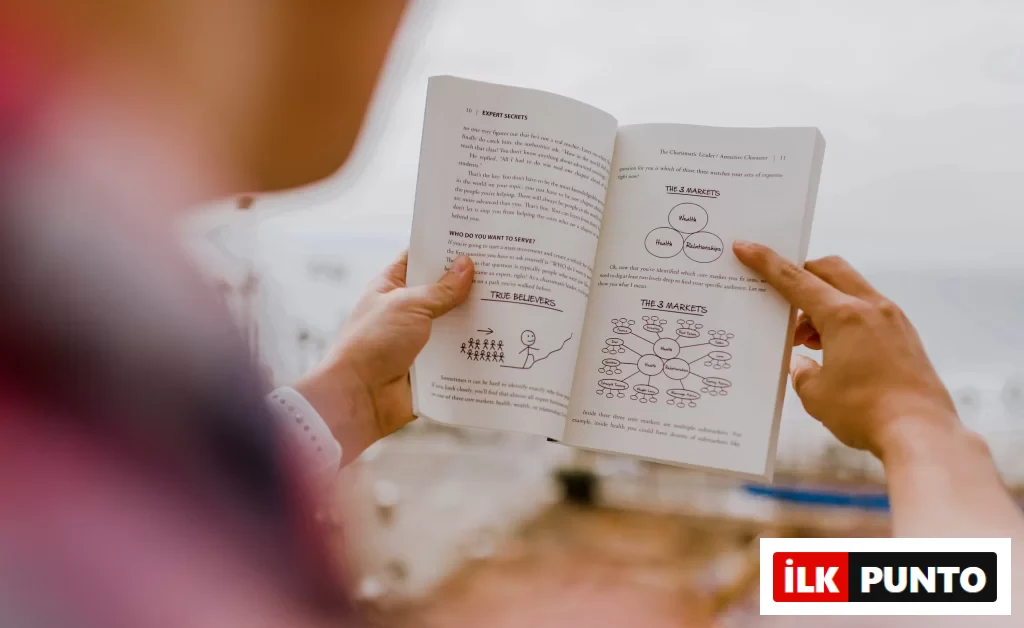 Bir kişi, içinde pazar segmentasyonu ve hedef kitle analizine dair şemaların bulunduğu bir iş kitabını açık havada inceliyor.