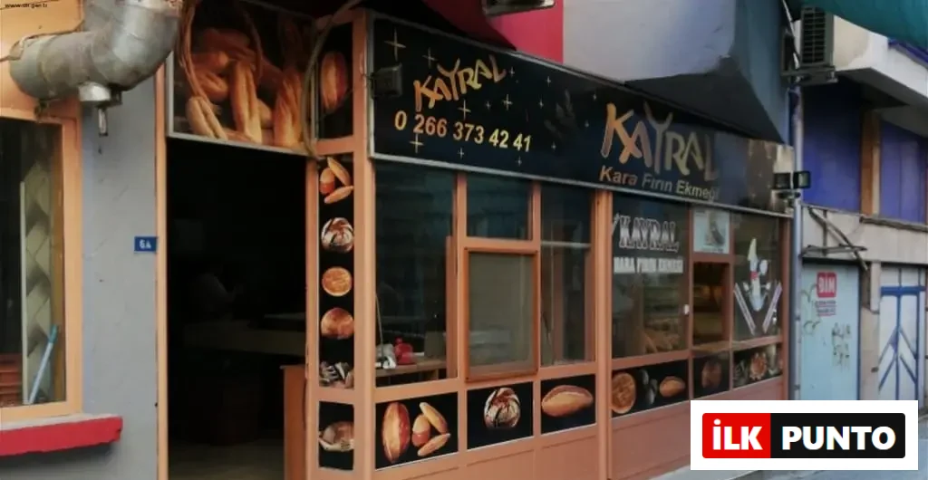 Kayral Kara Fırın Ekmeği tabelası, 0 266 373 42 41 telefon numarası ve dış cephesinde çeşitli ekmek çeşitlerinin görsellerinin sergilendiği, geleneksel ahşap çerçeveli cam vitrinlere sahip bir ekmek fırını görülmektedir.