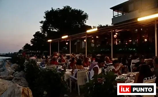 Edremit'in en iyi restoranları rehberinde yer alan deniz kıyısındaki restoranda canlı ve samimi akşam yemeği atmosferi.