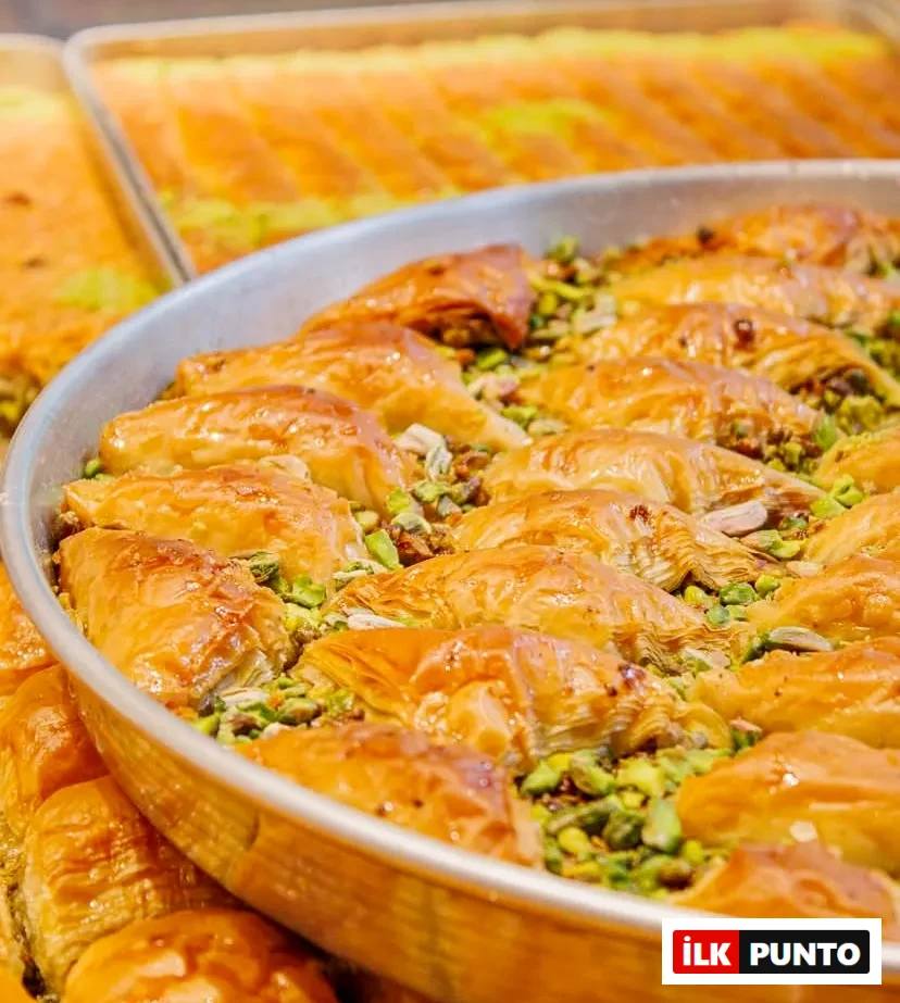 Büyük yuvarlak metal tepside özenle dizilmiş, incecik yufka katmanları arasından yeşil Antep fıstıkları taşan ve altın sarısı şerbetiyle parlayan çıtır midye baklavalar, Türk tatlı kültürünün eşsiz mirasını iştah açıcı biçimde sunuyor.