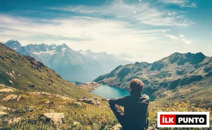 Uzaklarda uzanan bir vadi manzarasına bakan yürüyüşçü. Sessizlik, meditasyon ve iç yolculuk hissi.
