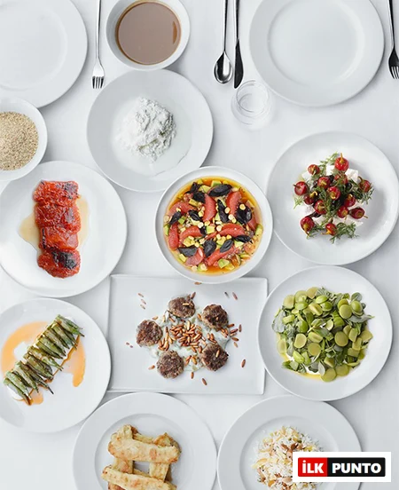 Antalya'daki en iyi restoranlardan birinde, geleneksel Türk ve modern Akdeniz mutfağının en lezzetli örneklerinden olan çam fıstıklı köfteler, taze sebzeli ve meyveli salatalar, pilav ve zengin meze çeşitleriyle bezenmiş beyaz bir masa kuşbakışı açıyla görülüyor.