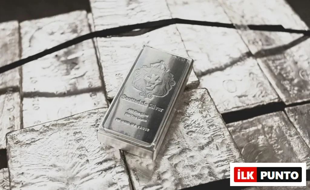 Parlak yüzeyli, üzerinde aslan figürü ve Scottsdale Silver yazısı bulunan bir gümüş külçesi, çevresindeki daha ham ve işlenmemiş birçok gümüş külçesinin üzerine konumlanmış olarak gümüş yatırımının hem tarihi önemini hem de günümüzdeki yaygınlığını gözler önüne seriyor.