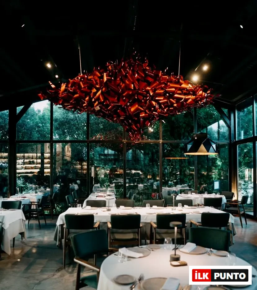 Od Urla restoranının camlarla çevrili şık iç mekânı, beyaz örtülü yuvarlak masalar ve dikkat çekici modern avize ile fine dining atmosferi