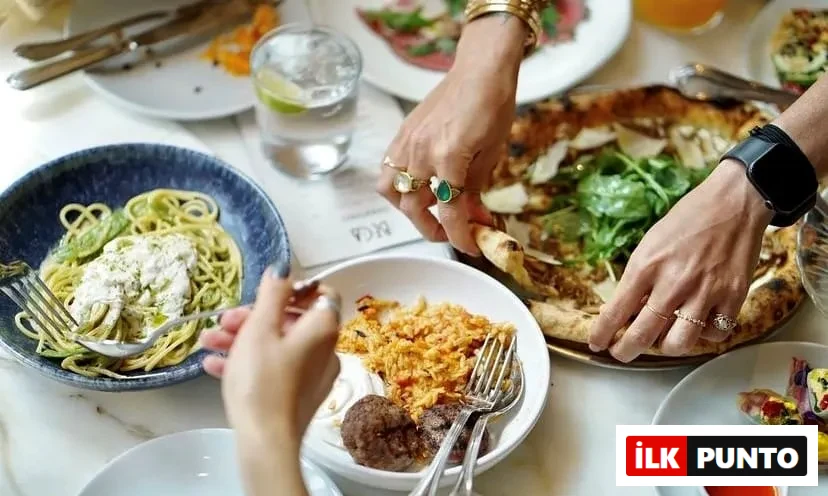 Beca İstanbul restoranında, bir masada pesto soslu spagetti, bol rokalı ve parmesan dilimli pizza, pilav ve köftenin yanı sıra çeşitli başlangıçların olduğu zengin bir yemek deneyimi yaşanırken, insanlar keyifle yemeklerini paylaşıyorlar.