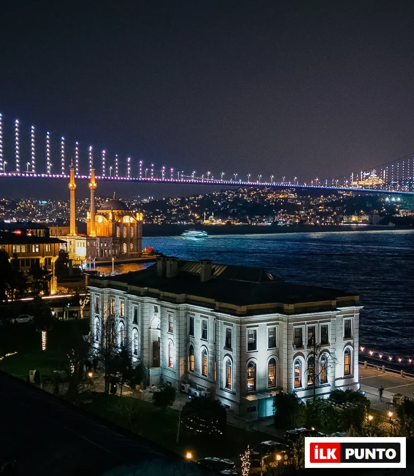 Boğaz kıyısında yer alan, ışıklarla aydınlatılmış tarihi Feriye binası, Ortaköy Camii ve Boğaziçi Köprüsü'nün göz alıcı gece manzarası, masmavi sular üzerinde parlayan şehir ışıklarıyla birlikte İstanbul'un eşsiz güzelliğini yansıtmaktadır.