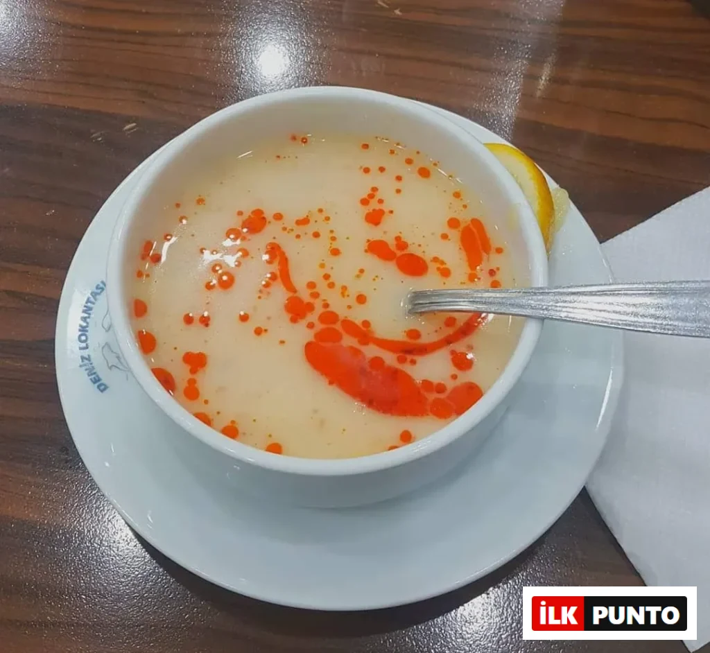 Deniz Lokantası’nda servis edilen tavuklu yarma çorbası, kırmızı yağ sosu ve limon dilimiyle birlikte sunulmuş