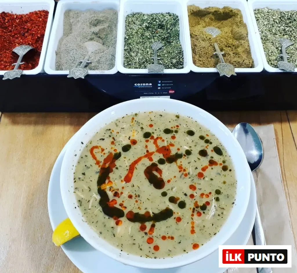 Hebun Çorba Evi’nde servis edilen mercimek çorbası, üzerine nane ve kırmızı yağ gezdirilmiş, yanında kaşık ve limonla sunulmuş.