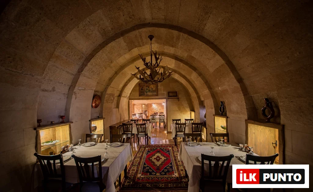Kapadokya'nın tarihi dokusunu yansıtan eşsiz mekanlardan Old Greek House'un, kemerli taş duvarları, zarif masa düzenlemeleri, renkli otantik halısı ve sıcak bir atmosfer yaratan aydınlatmasıyla dolu iç restoran alanı.