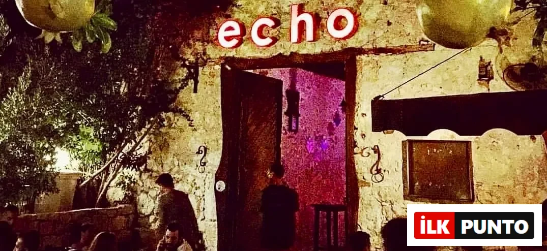 echo adlı mekanın kırmızı neon tabelasının altında, eski taş duvarlı bir binanın geniş açık kapısından içeri sızan mor ışığın aydınlattığı, ağaçlar ve loş aydınlatmalarla çevrili dış alanda sosyalleşen misafirler görülüyor.