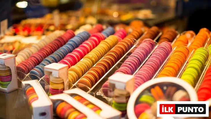 Pastane vitrininde sıralanmış rengarenk makaronlar – çikolatalı, frambuazlı, limonlu ve fıstıklı çeşitler