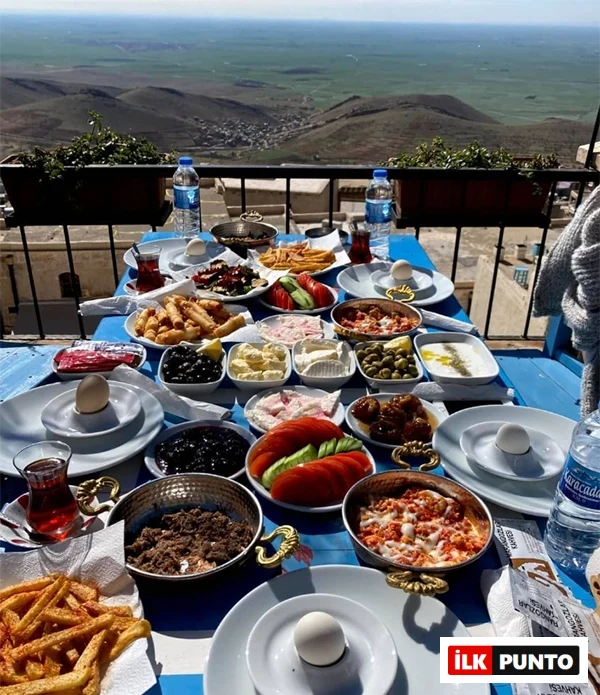 Mardin'in nefes kesen vadi manzarasına hakim bir balkonda, mavi beyaz çizgili bir masada serili, kızarmış patates, haşlanmış yumurta, siyah ve yeşil zeytinler, peynir çeşitleri, menemen ve kıymalı yumurta gibi onlarca lezzetli yiyeceğin bulunduğu zengin bir Türk kahvaltısı.