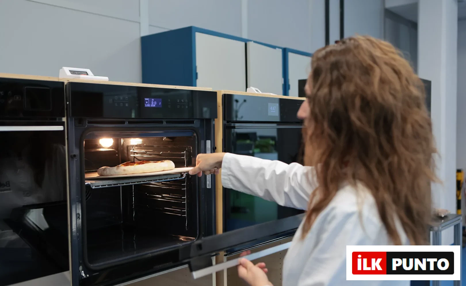 Modern, aydınlık bir Food Tech Lab mutfak ortamında, ankastre fırın, şık bir indüksiyonlu ocak ve stand mikser gibi çağdaş beyaz eşyalar, İtalya'daki tesislerde geliştirilen yapay zekâlı mutfak teknolojileri ve sessiz lüks tasarım felsefesini yansıtan detaylarla sunuluyor.