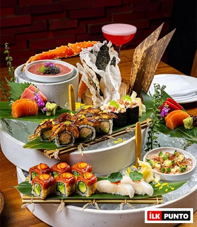 Bu görsel, İstanbul’un en popüler sushi restoranlarında sunulan zengin ve göz alıcı bir menüyü, buz üzerinde özenle sergilenmiş yılan balığı roll’ları, taze ton ve somon sashimi’ler, yengeç bacağı ve çeşitli nigirilerle modern Uzak Doğu mutfağının rafine lezzetini yansıtan bir şöleni detaylandırıyor.