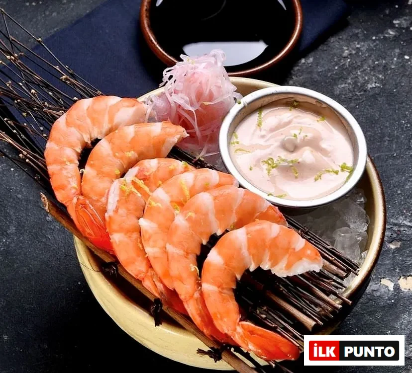 İstanbul'un en iyi sushi restoranlarından birinde sunulan, kuru otlar üzerinde buzla sergilenen limon zestli taze haşlanmış karidesler, özel kremsi sosu ve hafif pembe turşu garnitürüyle Uzak Doğu mutfağının rafine deniz mahsulleri sunumunu yansıtıyor.