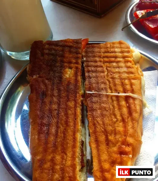 Muğla Akçapınar Tostçusu: yol üstü tost duraklarının efsanesi. Büyük porsiyonlu tost, yanında ayran ve turşuyla servis ediliyor.