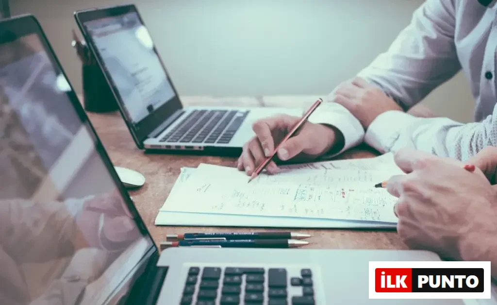 İki kişi masada laptop ve belgeler üzerinden finansal strateji toplantısı yapıyor.