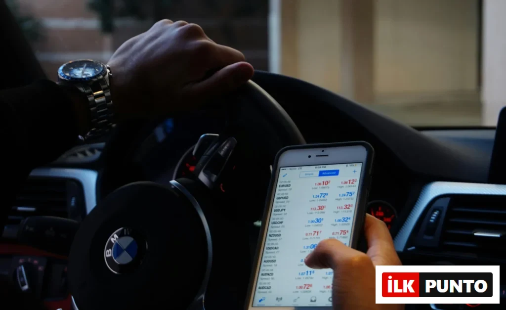 Bir sürücü, BMW aracının içinde döviz ve yatırım piyasalarını mobil uygulama üzerinden anlık olarak takip ediyor.